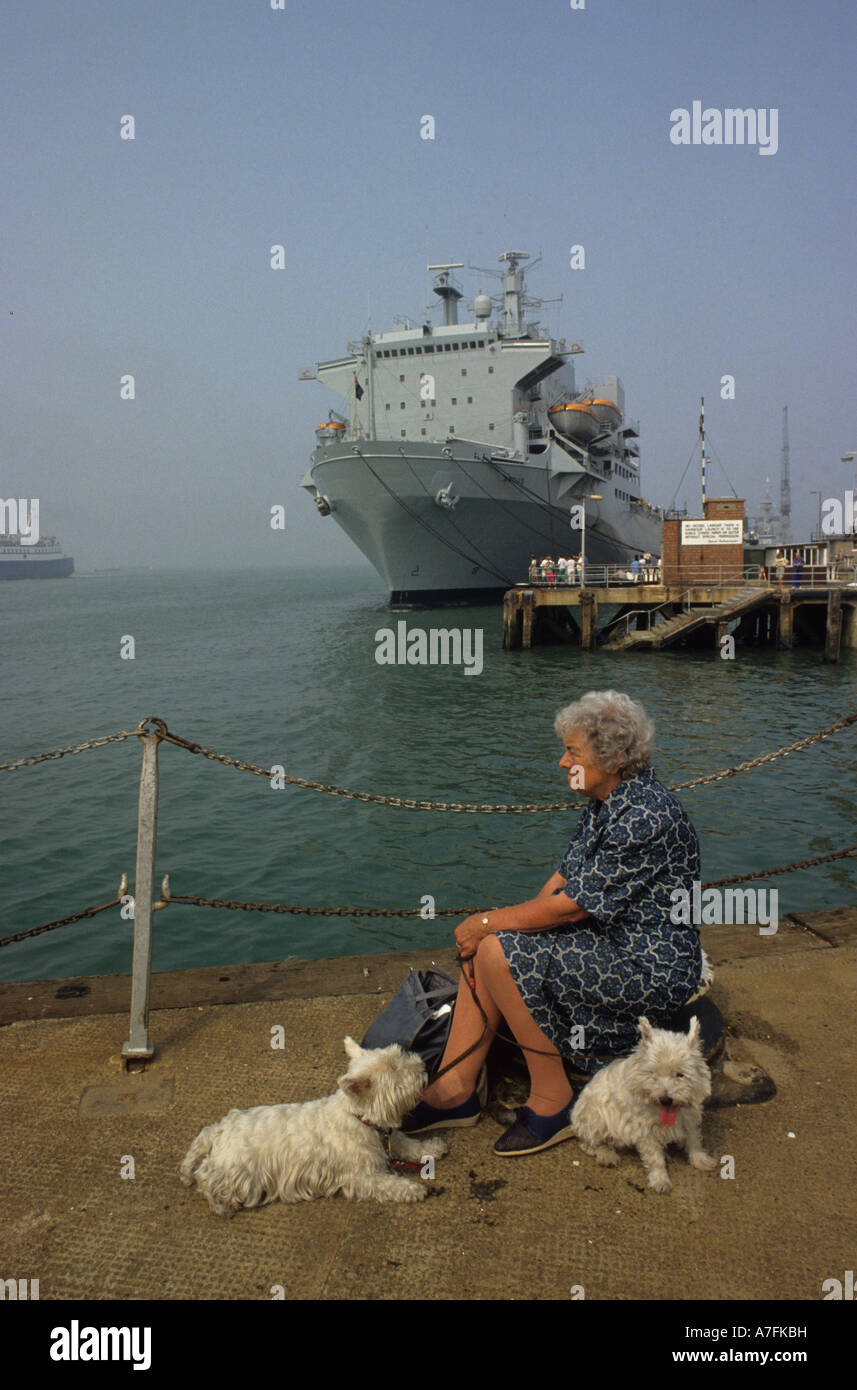 Portsmouth-Dockyard.Woman mit 2 Hunden erholend vor Marineschiff Stockfoto