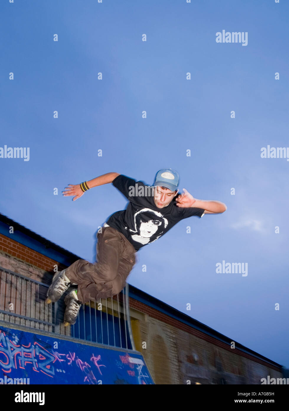 18 Jahre alte Männchen machen aggressive Inline skating Tricks auf Quarter-Pipe in UK skatepark Stockfoto