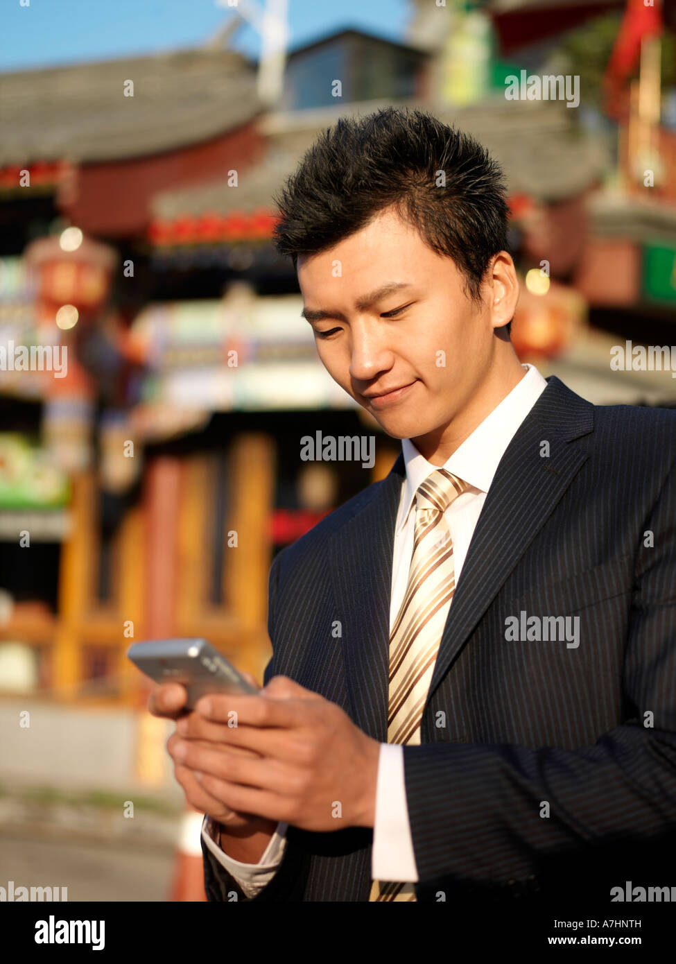 Ein junger chinesischer Geschäftsmann im Anzug Überprüfung sein Handy Stockfoto