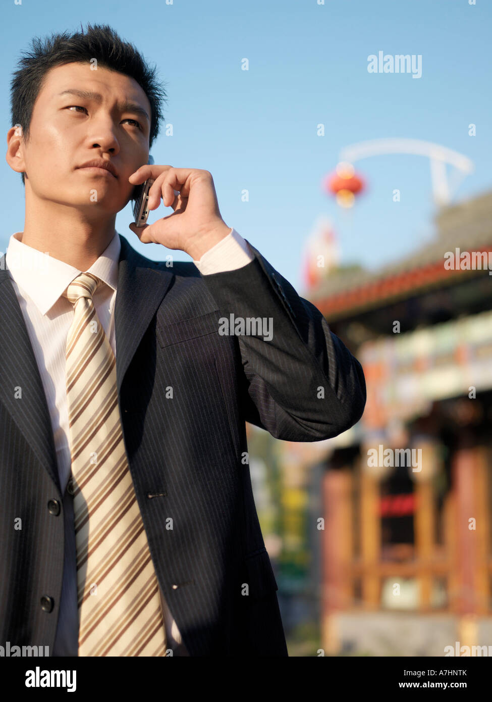 Ein junger chinesischer Geschäftsmann im Anzug auf seinem Handy zu sprechen Stockfoto