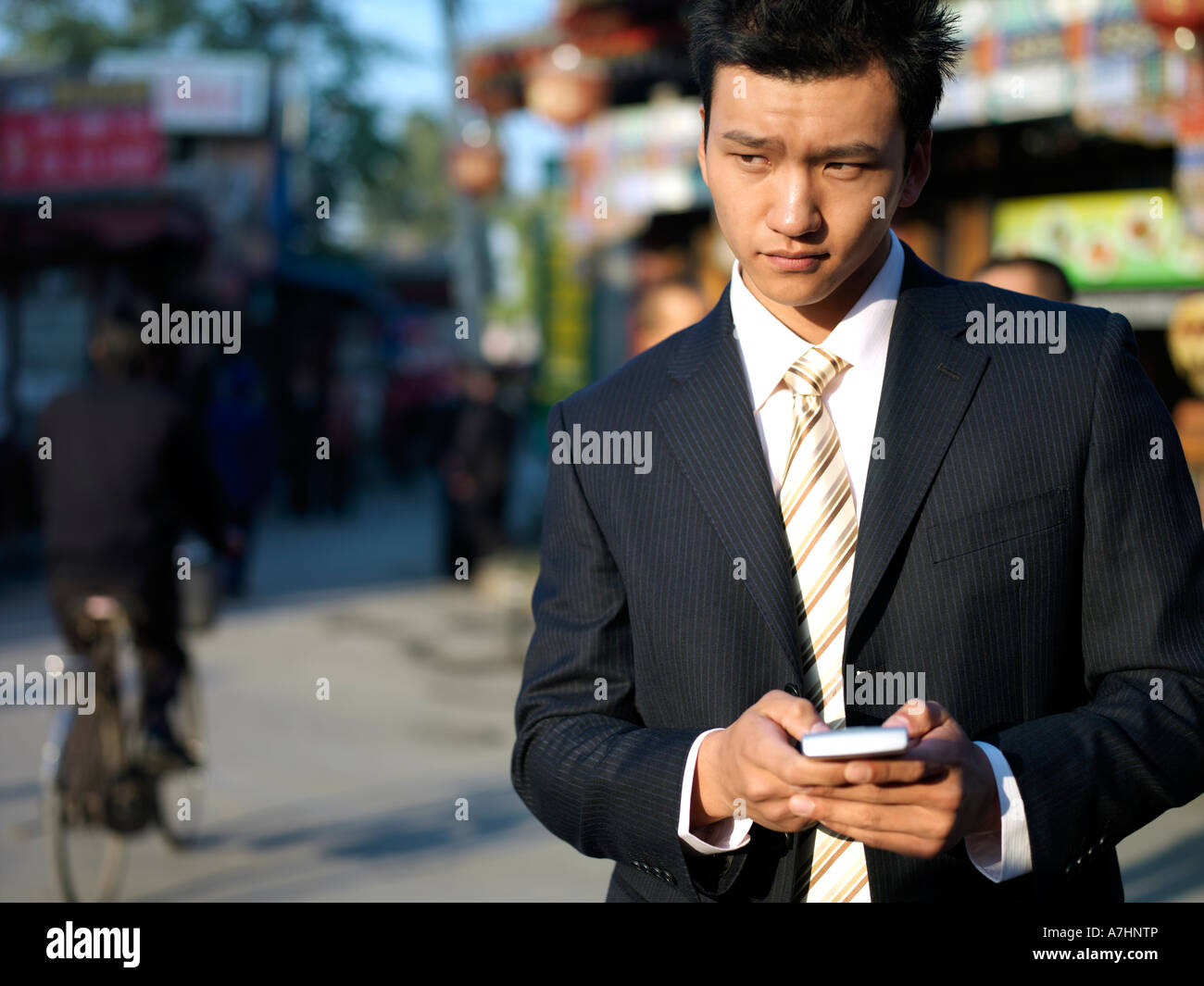 Ein junger chinesischer Geschäftsmann im Anzug Überprüfung sein Handy Stockfoto