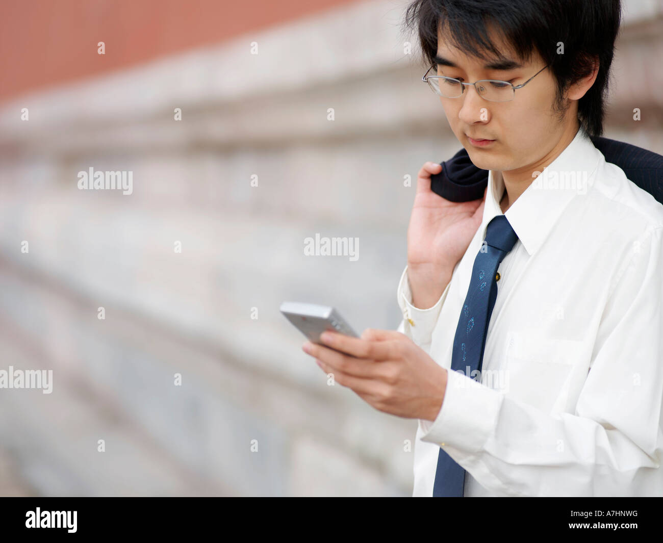 Ein junger Chinese Business Mann in einem Anzug überprüft seine Telefon Stockfoto