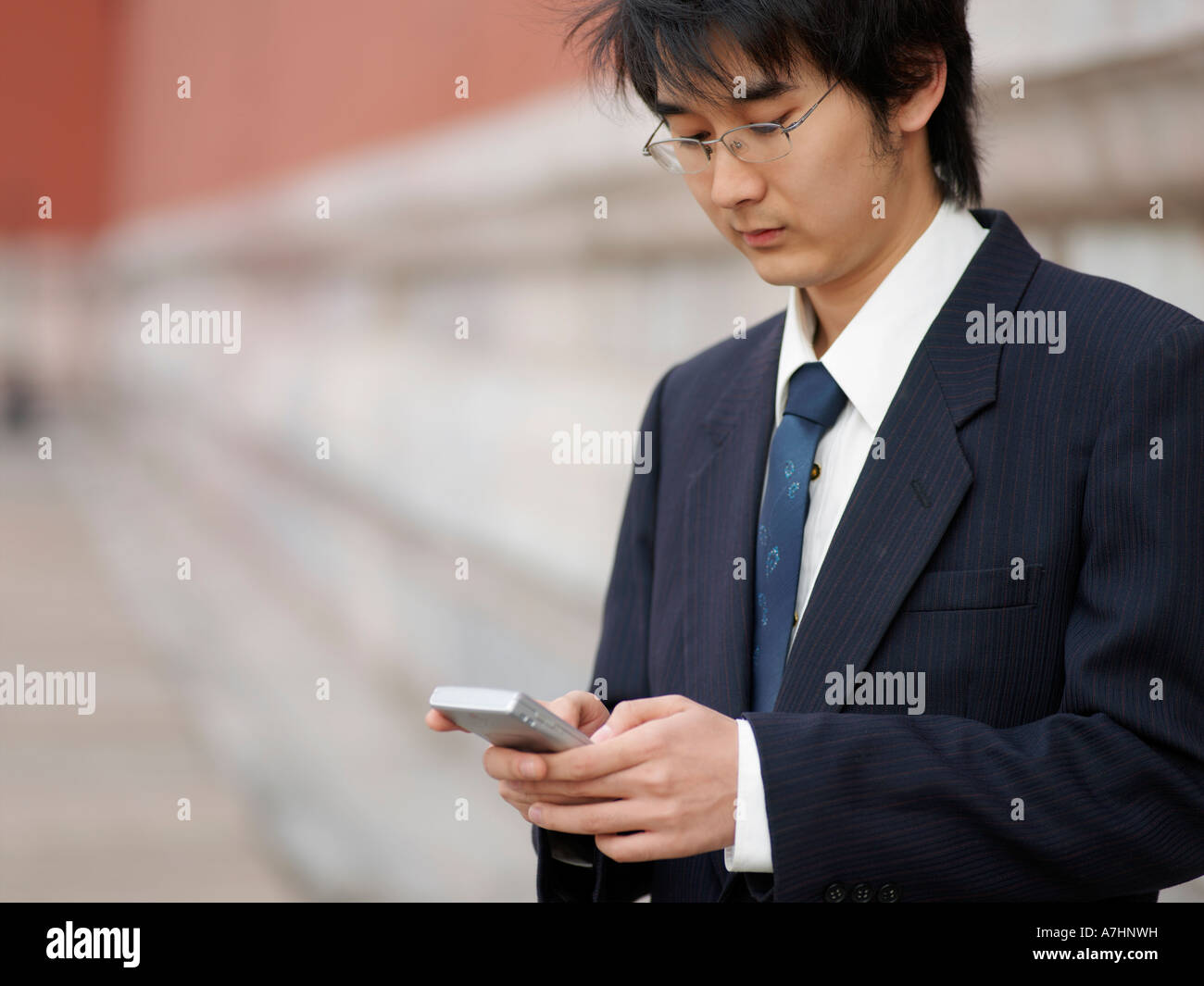 Ein junger Chinese Business Mann in einem Anzug überprüft seine Telefon Stockfoto