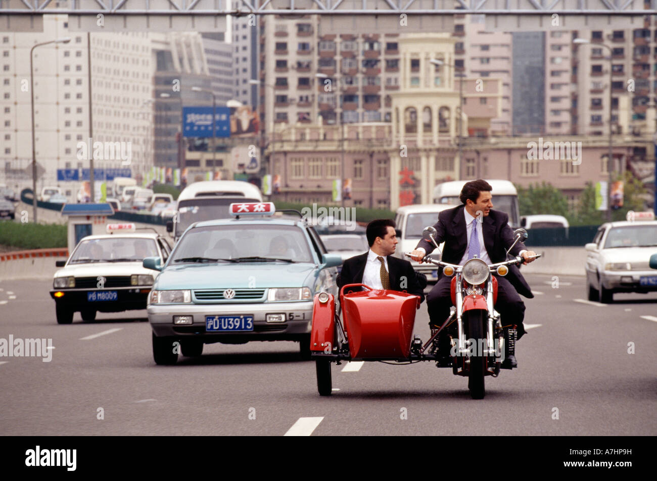 Zwei Kaukasier in Business-Anzügen, die Senkung der chinesischen Autobahn auf einem Fahrrad in China Stockfoto