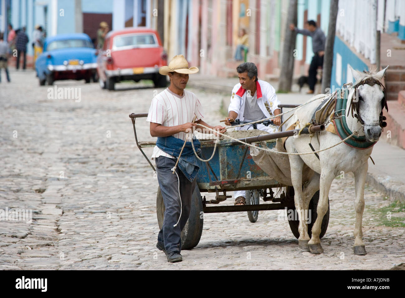 Kubanische führt Mörtel - geladenen Wagen auf einer gepflasterten Straße in Trinidad, Kuba: Zigarre rauchen Radfahrer auf Rückseite. Stockfoto