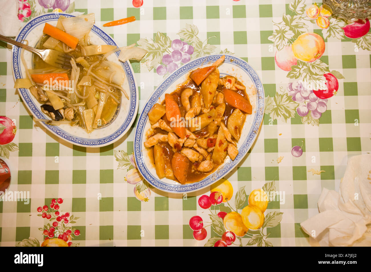 Zwei Platten der chinesischen Gericht auf einem Tisch mit geprüften Kunststoff-Abdeckung mit Obst-Design. Stockfoto