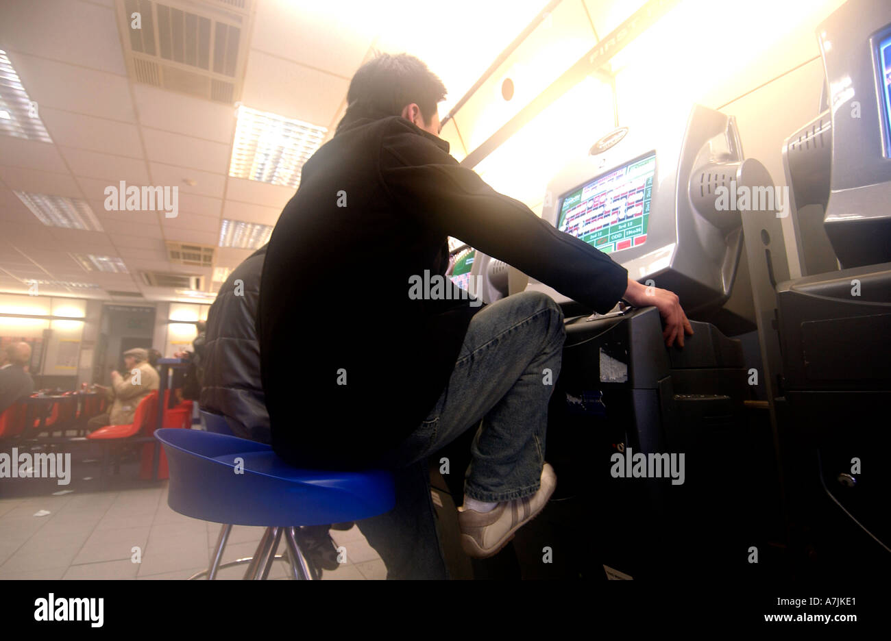 Eine junge männliche Spieler spielt eine Roulette-Maschine in einem Wettbüro Stockfoto
