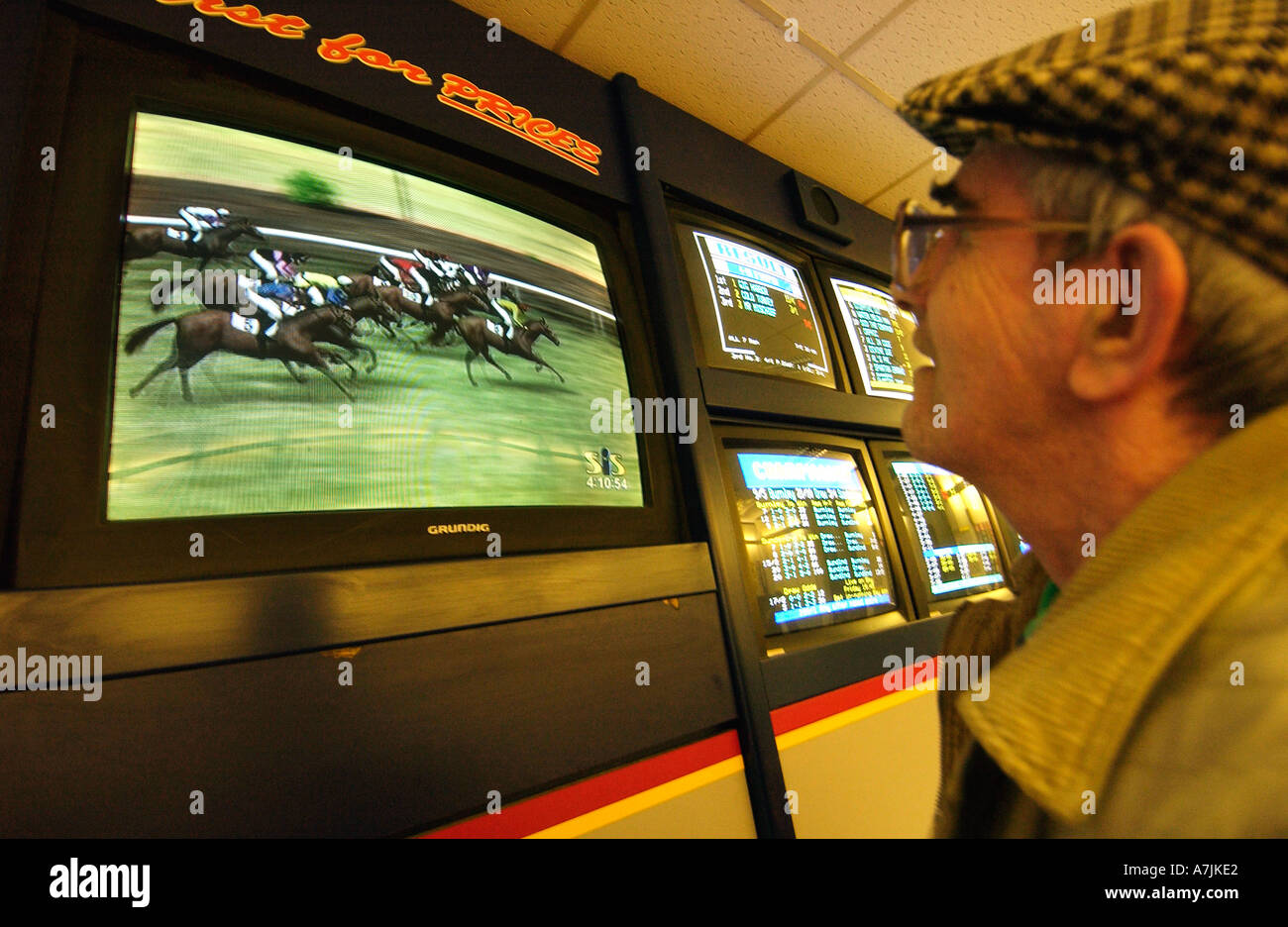 Alter Mann in Tuch Mütze gerade eine Pferderennen auf dem TV-Bildschirm im William Hill Stockfoto