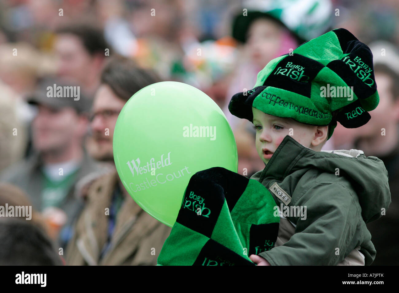 kleiner Junge auf Väter Schultern mit grünen und schwarzen Hut mit grüner Ballon in der Menge am St. Patricks Day Konzert belfast Stockfoto