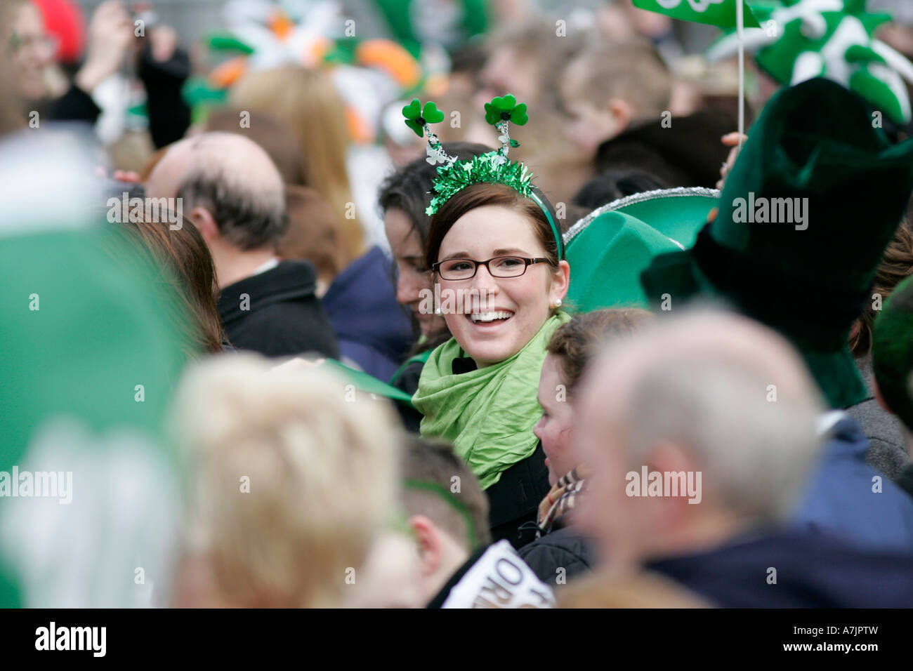 rot braun Mädchenakt Brillen-und grünen Schal lächelnd in die Menge am St. Patricks Day Konzert Belfast Stockfoto