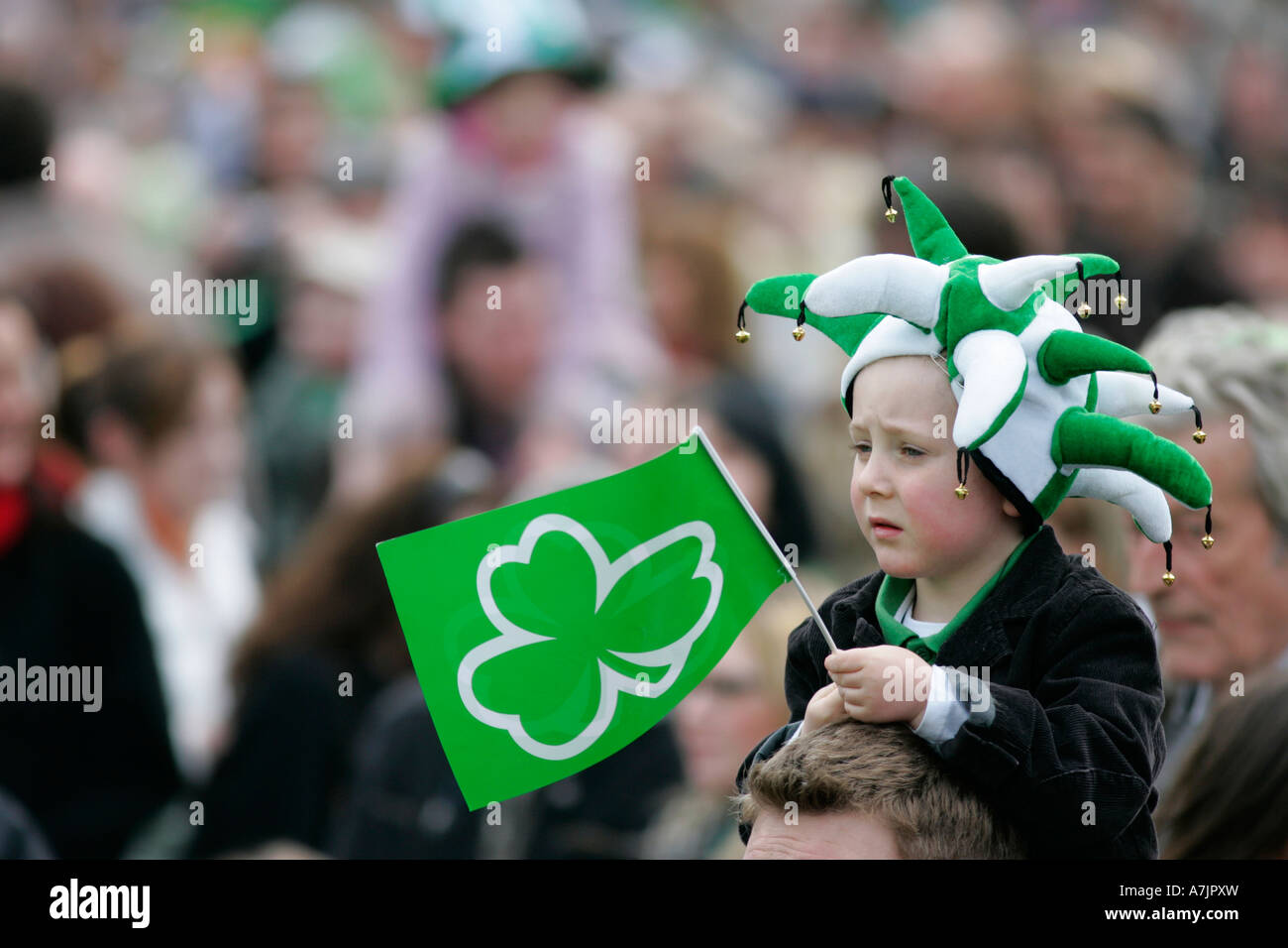 junge grüne und weiße Narren Hut trägt und hält grüne Kleeblatt Flagge in der Menge am St. Patricks Day Konzert Belfast Stockfoto