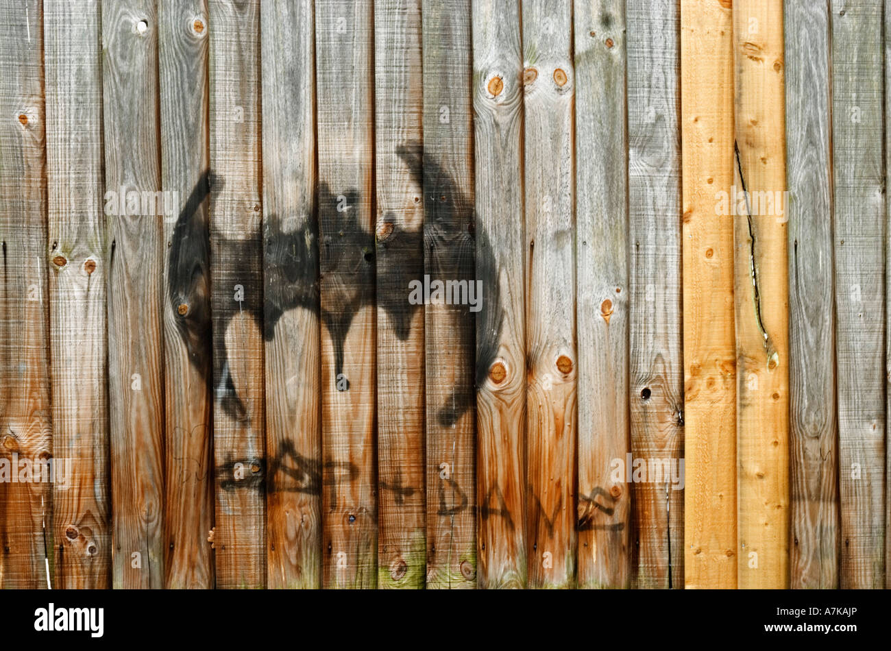Graffiti an einem Holzzaun, in Form von einem Batman-Logo. Stockfoto