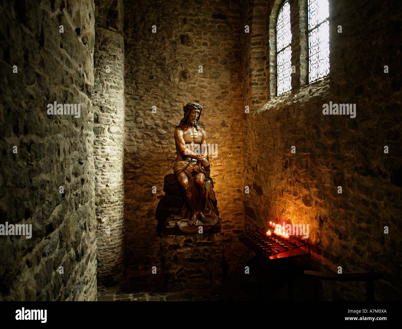 Dramatische Jesus Christus in einer historischen römischen Kirche in Brugge Brügge Belgien mit brennenden Kerzen Stockfoto