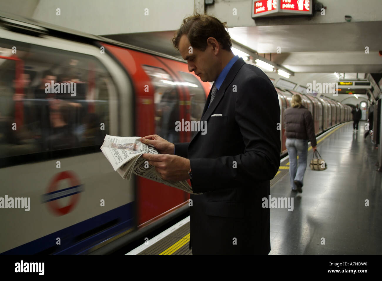 Stadt Gent Zeitungslektüre auf der Londoner U-Bahn Station mit Zug nähert sich England-Großbritannien Stockfoto