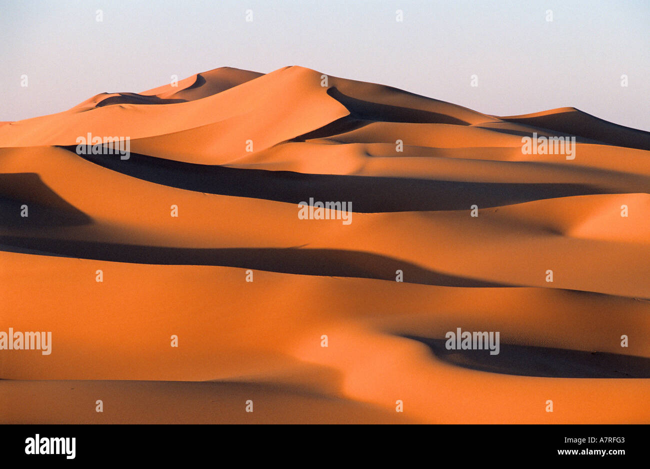 Libyen, Region der Wüste, Fezzan (Sahara), ockerfarbenen Dünen und hohen Leiste aus Sandstein des Tadrart Akacus im Nordosten von Ghat Stockfoto