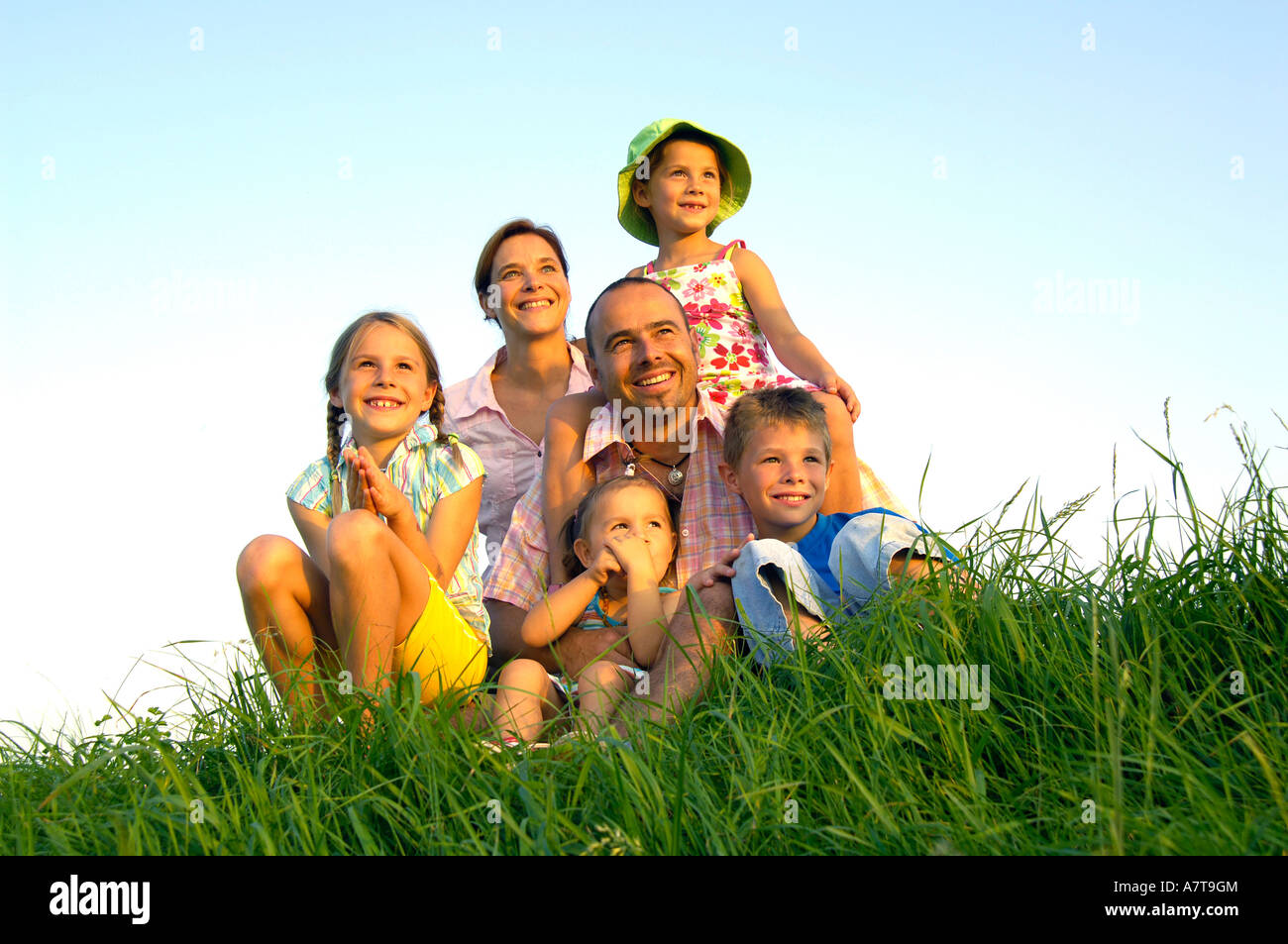 Familie sitzt im Feld Stockfoto