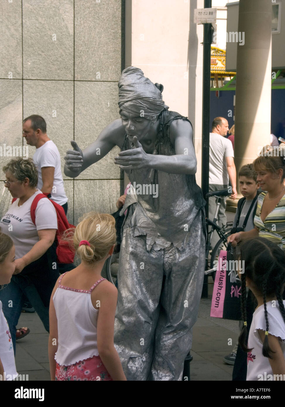 Silber Painted Street Performer Entertainer mit Kindern Covent Garden London WC2 England Turban lustigen Hut Pantomime Stockfoto