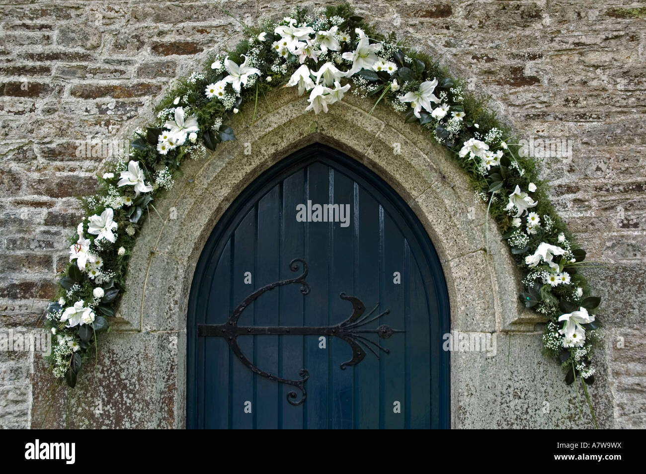 die Eingangstür in der st.mawnan Kirche in der Nähe von Falmouth, Cornwall, England, dekoriert mit Blumen für die Osterfestspiele Stockfoto