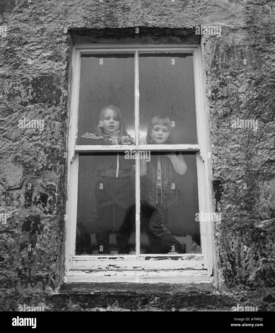 Zwei Kinder stehen im Landhaus aus Stein-Fenster auf der Isle of Mull Schottland UK Stockfoto