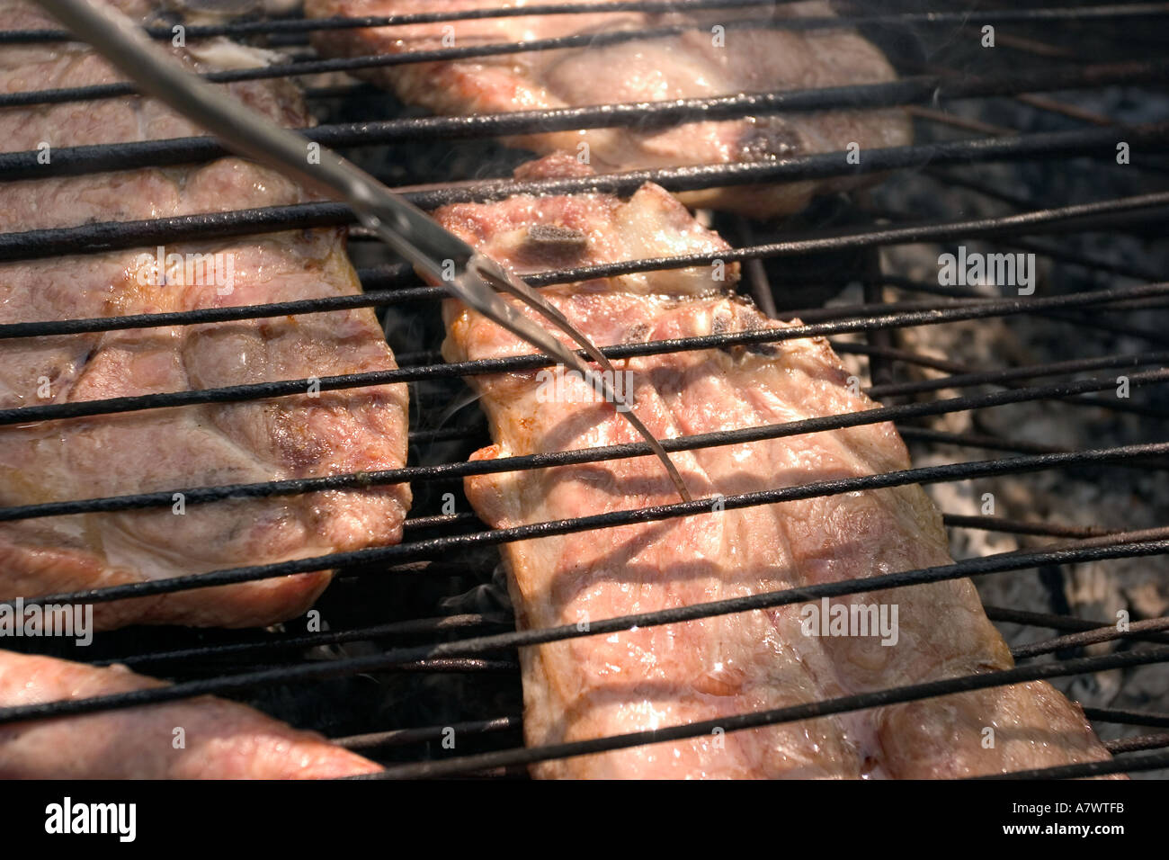 Gegrilltes Fleisch am Grill grill mit Fourch und Hand des Menschen Stockfoto