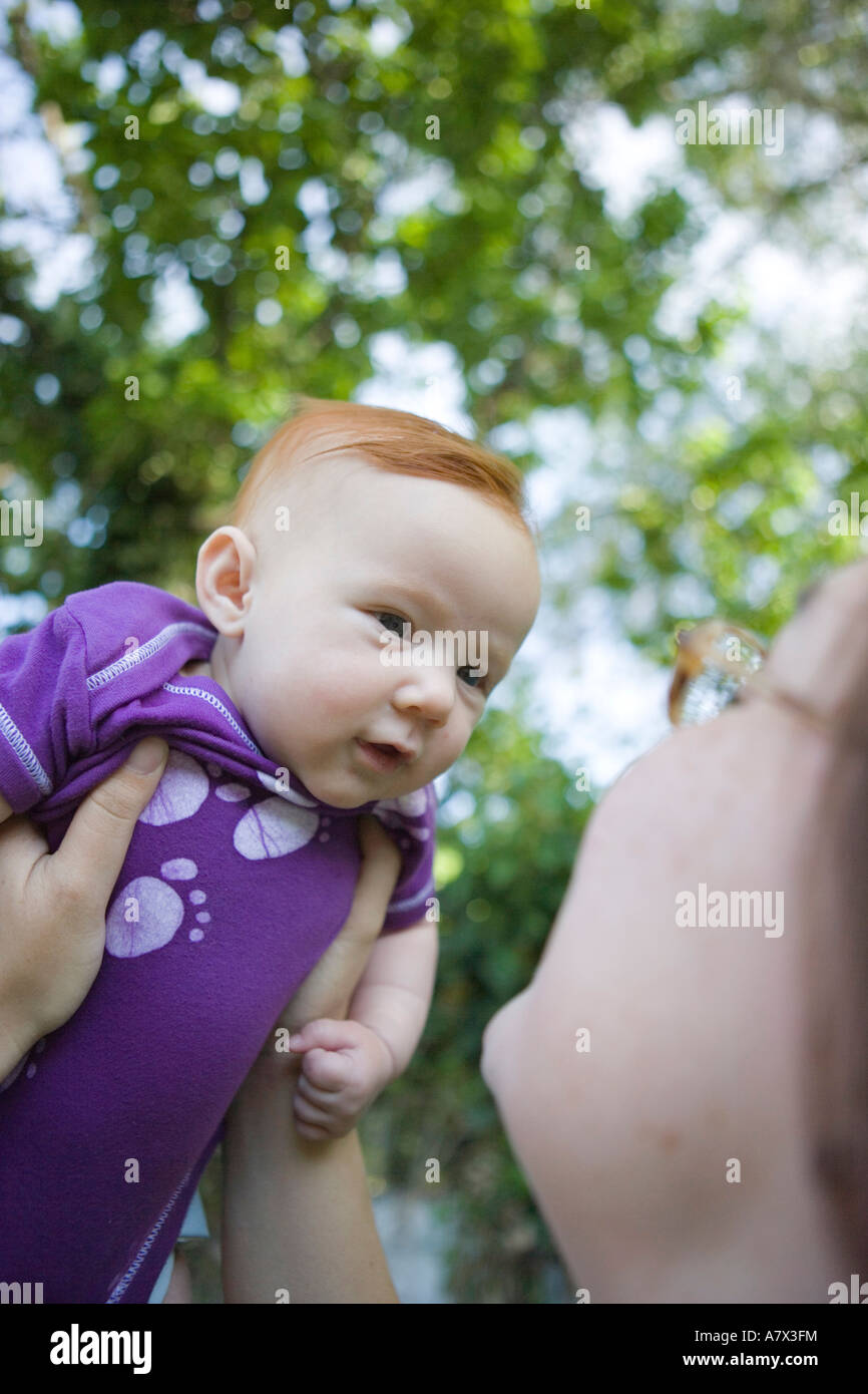drei Monate altes Baby Mädchen beobachten Mama mit ihr zu reden, während im Freien gehalten, von Angesicht zu Angesicht Stockfoto