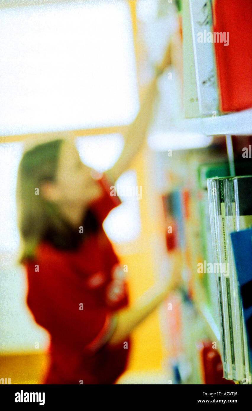 junge Frau in Bibliothek Bücher wieder sehr bunten Bücher setzen möglicherweise Kunstbücher, die Sie Lächeln Spaß an ihrer Arbeit Stockfoto