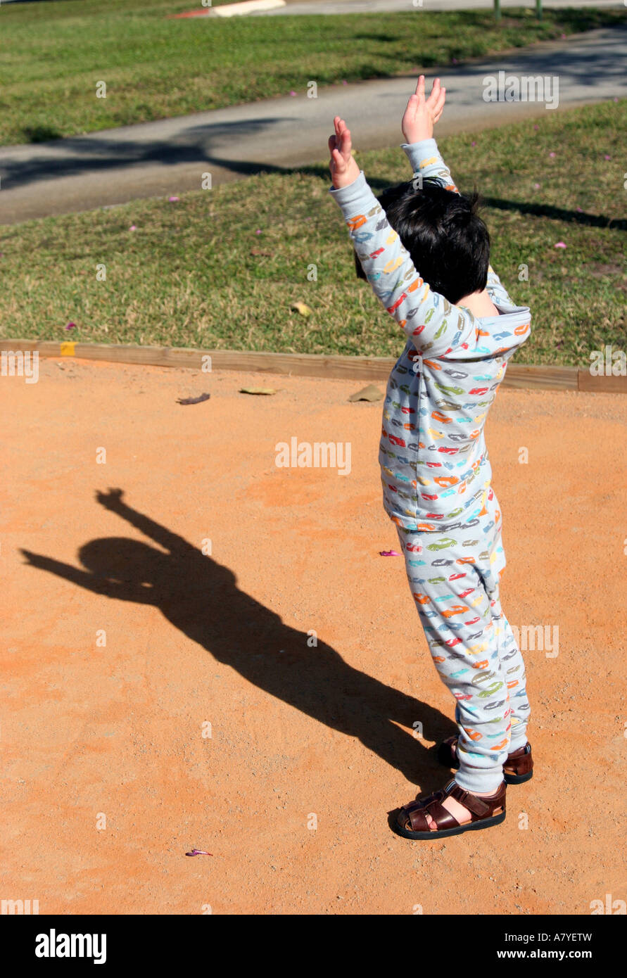 Junge (ca. 3-4 Jahre alt) stand im Pyjama bewundern seinen Schatten Stockfoto