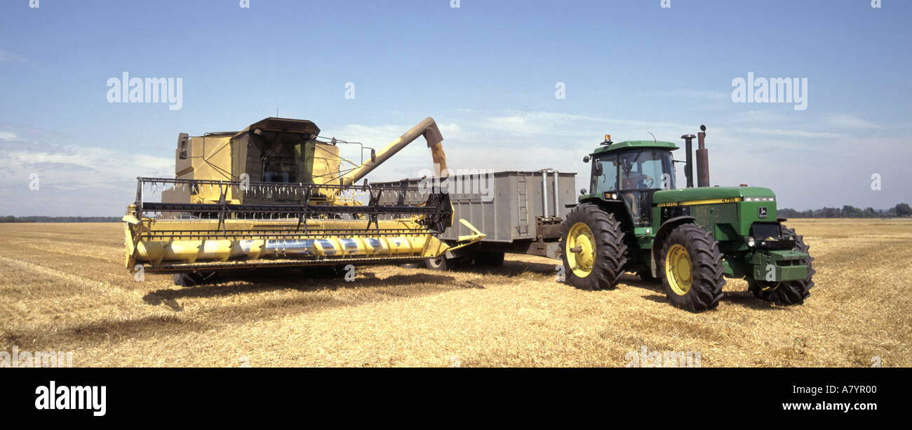 Landwirtschaft Landwirtschaft Ernte Stoppeln Combine Harvester entladen Korn zum trailer bin John wartet Deere Traktor, um Last aus Essex England UK Feld zu bewegen Stockfoto