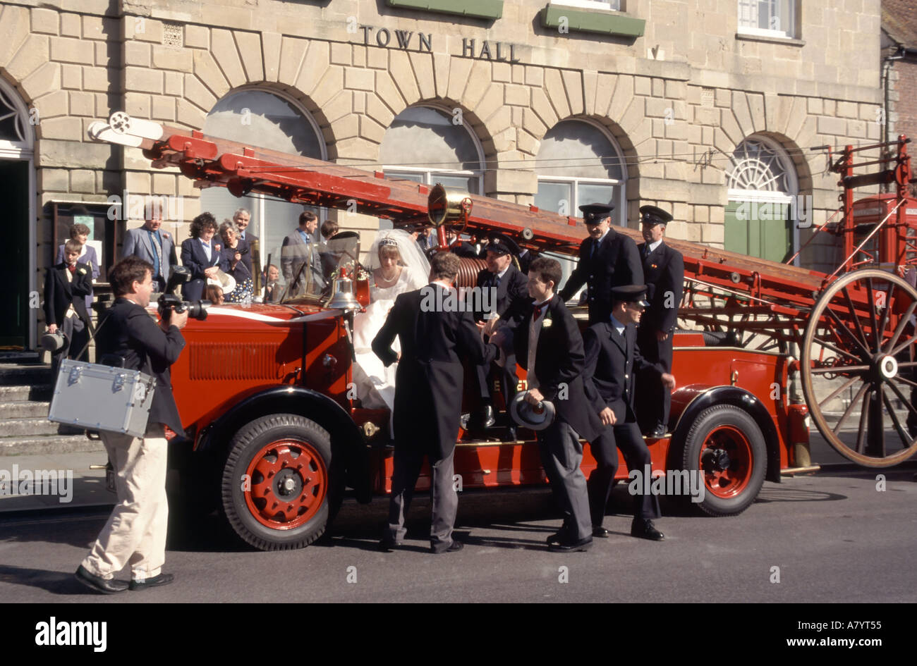 Glastonbury Hochzeitsgäste auf und um restaurierte altmodische Feuerwehrmaschine vor dem Rathaus geparkt Fotograf Besuch Somerset England Großbritannien Stockfoto