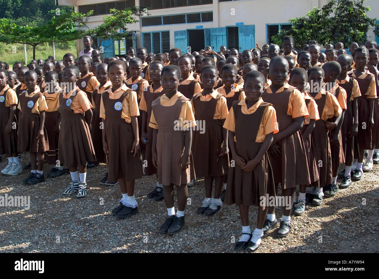 Gemischte Gruppe von jungen Mädchen Schulkinder aufgereiht für die Montage außerhalb Schulgebäude - vor Klassen in Ghana, Westafrika Stockfoto