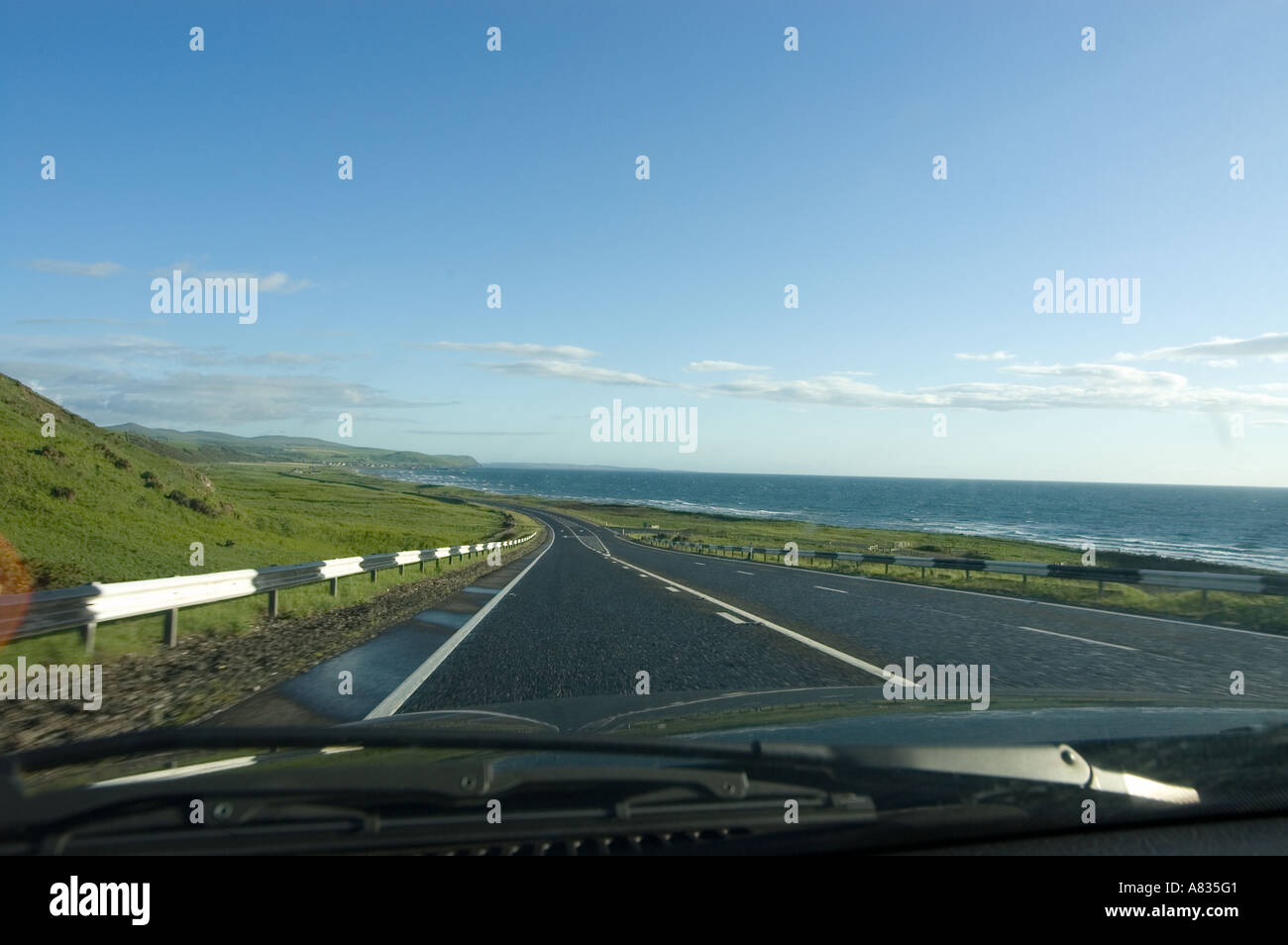 Landschaft des hügeligen Küste mit einer Straße vor, gesehen durch die Windschutzscheibe eines Autos Stockfoto