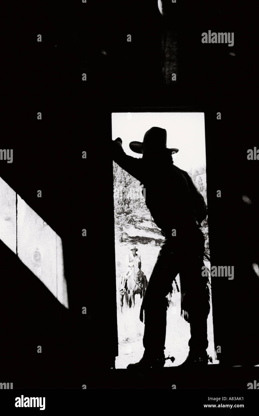 Ein Cowboy in der Tür einer Scheune in Oregon mit einer anderen Cowboy Reiten im Hintergrund stehe Stockfoto