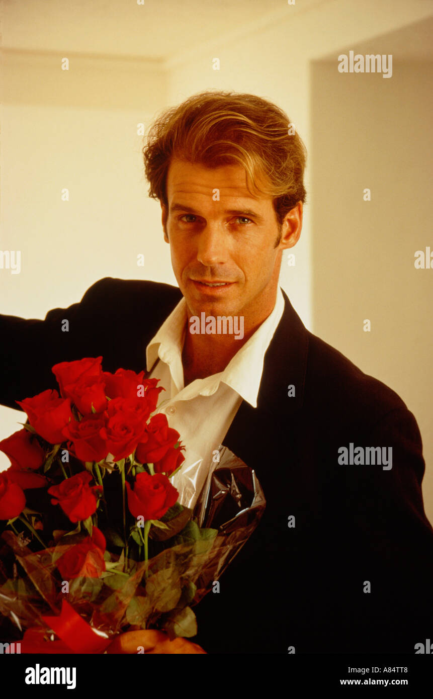 Indoor Porträt junger Mann, Blumenstrauß aus roten Rosen. Stockfoto