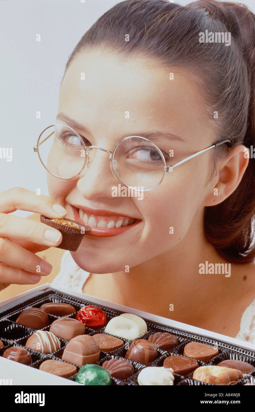 Studio-Porträt der Frau etwa, eine Schokolade aus einer Auswahlbox zu essen. Stockfoto