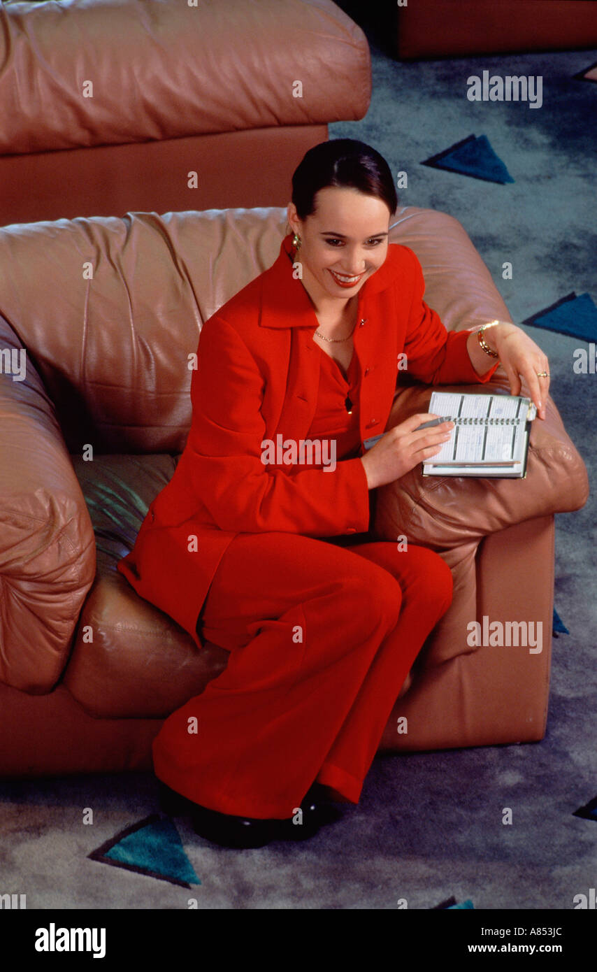 Hohe Sicht der jungen Frau in roten Hosenanzug in Ledersessel sitzend  Stockfotografie - Alamy