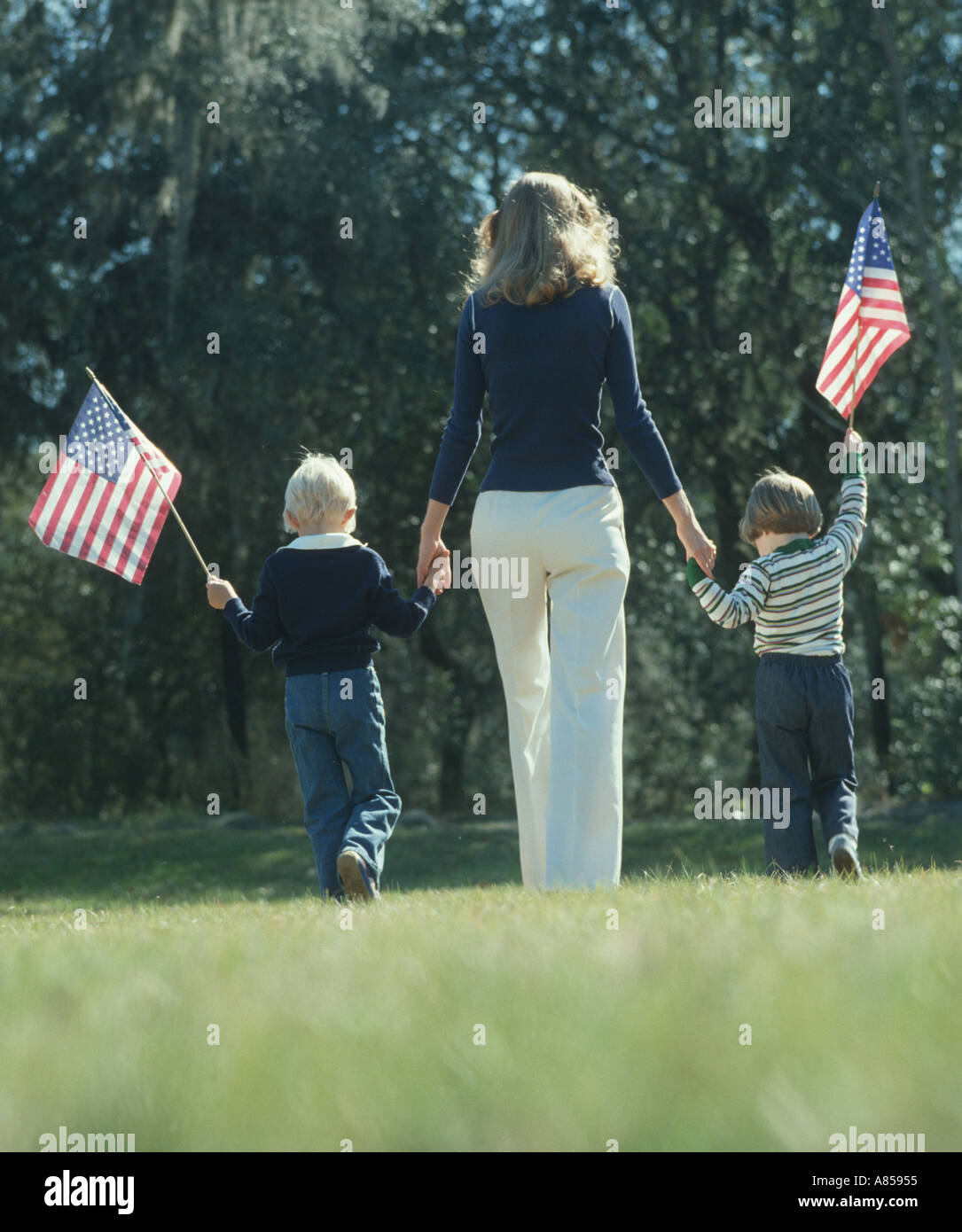 Mutter und zwei Kinder mit amerikanischen Fahnen im park Stockfoto