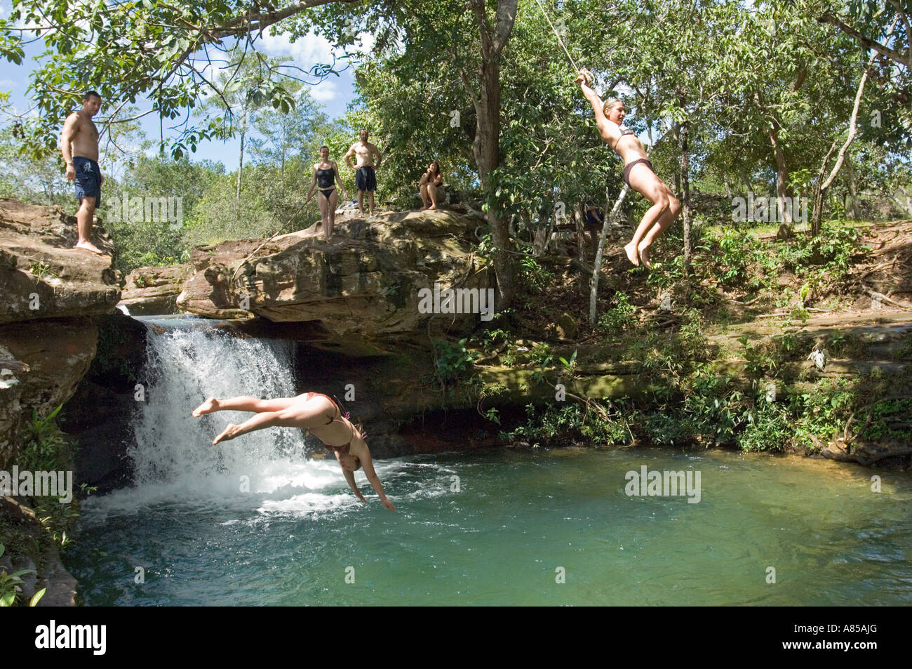 Eine Gruppe von europäischen Touristen in Brasilien abkühlen auf einem Campingplatz, Tauchen und springen von einem Seil Schaukel in einem Süßwasser-Pool. Stockfoto