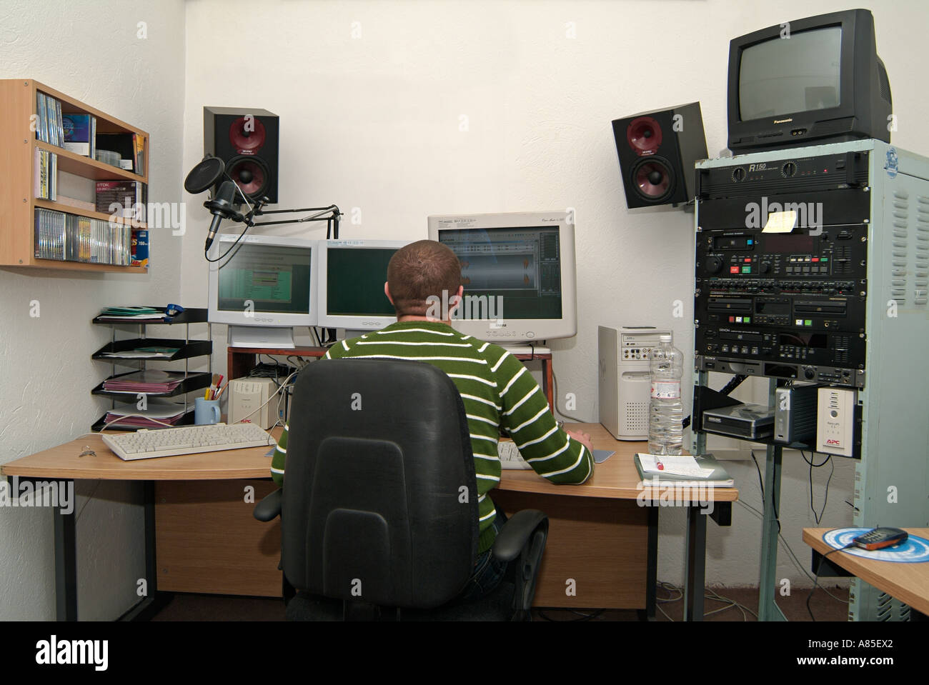 Männliche Sat an einem Computerarbeitsplatz im Produktionsstudio eine kommerzielle Radiostation Stockfoto