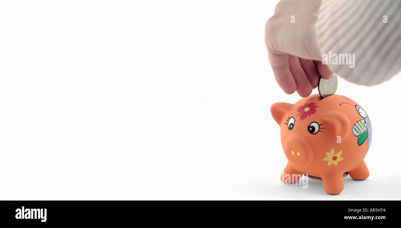 Frauen-Hand, eine Münze in ein Sparschwein Stockfoto