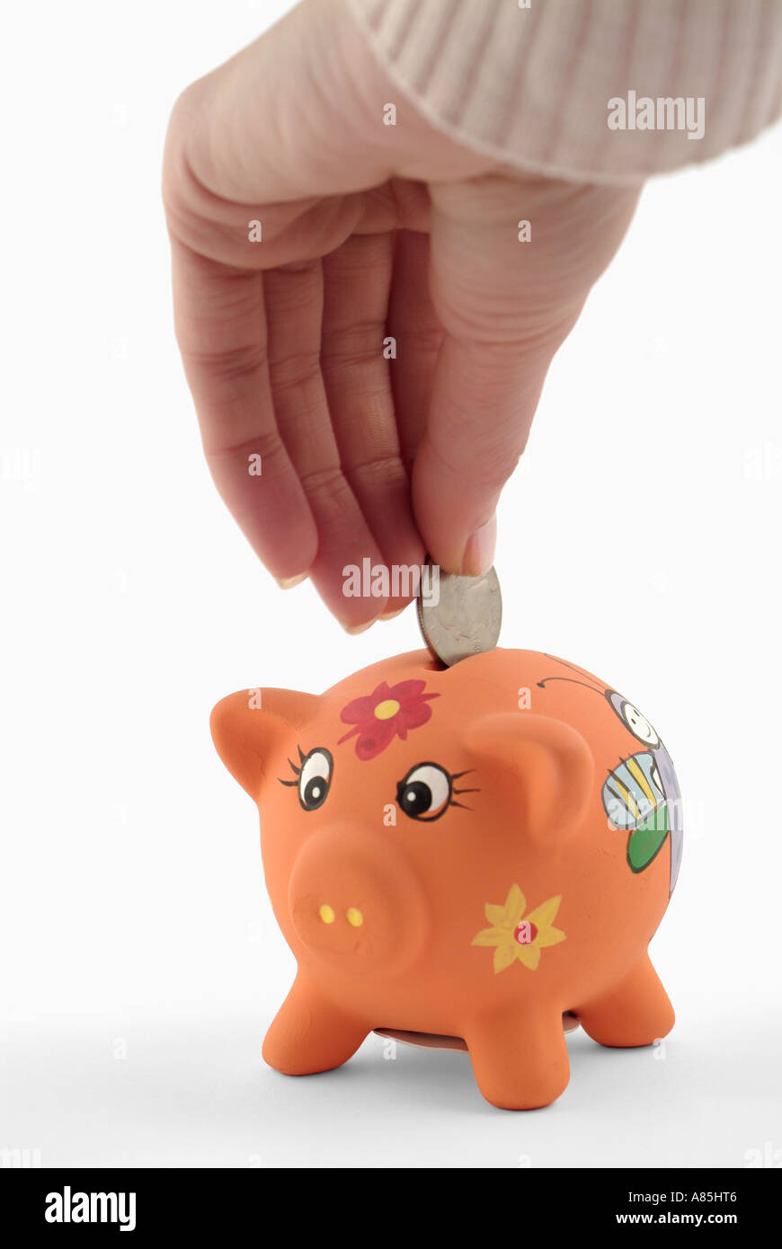 Frauen-Hand, eine Münze in ein Sparschwein Stockfoto