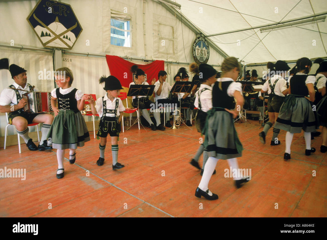 Kinder tanzen in bayerischer Tracht zu traditioneller Musik auf dem Oktoberfest in München Stockfoto