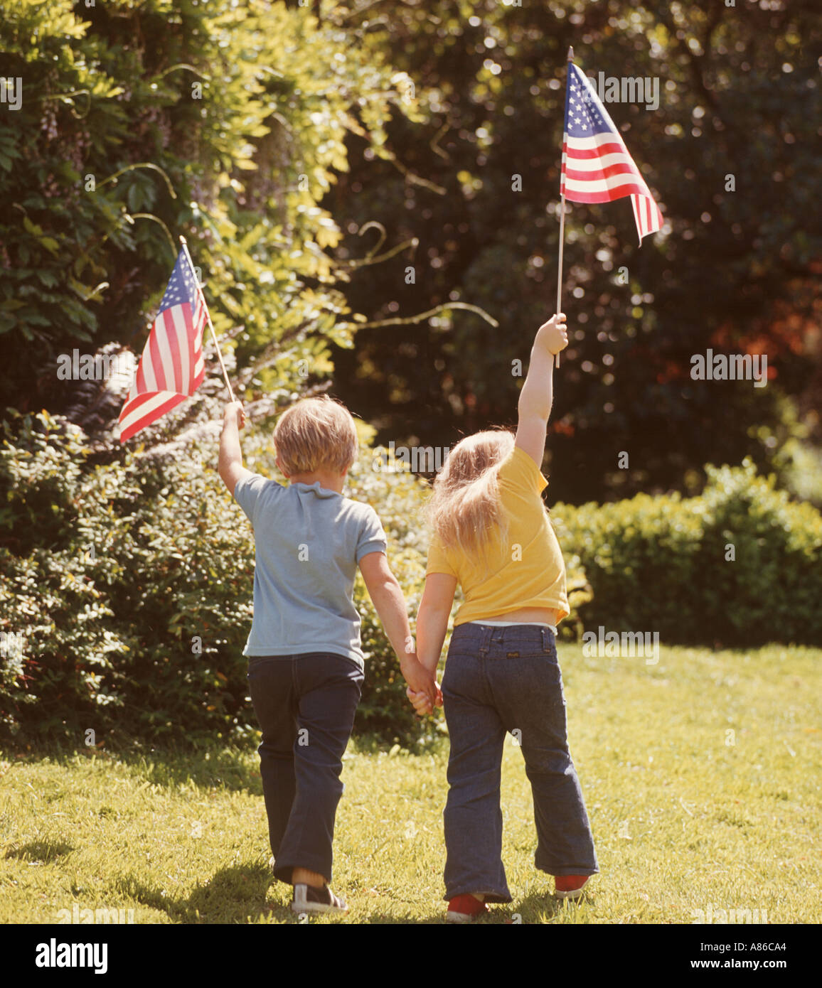 kleine Jungen und Mädchen mit kleinen amerikanischen Fahnen im park Stockfoto
