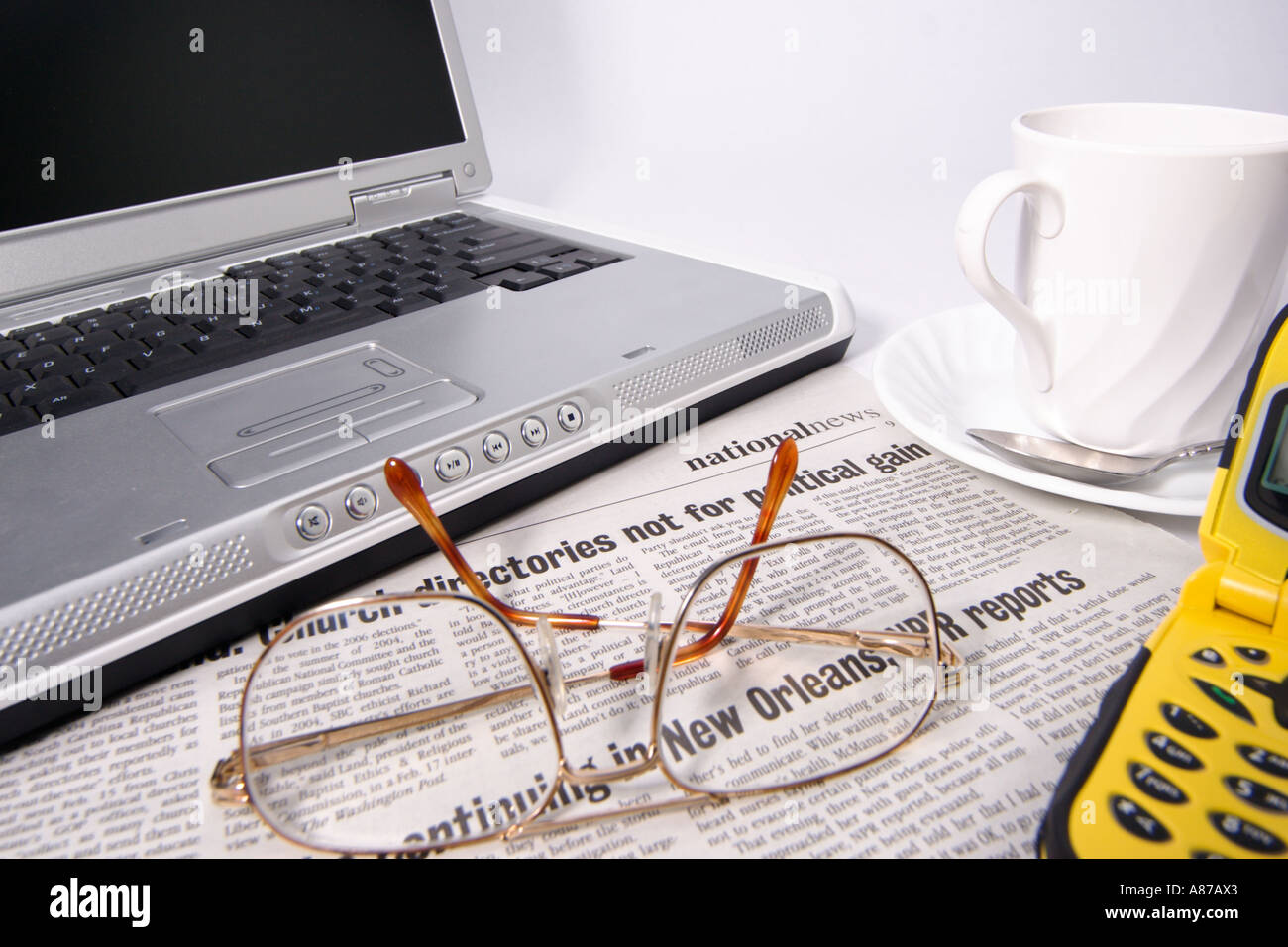 Offenen Laptop Notebook-Computer mit Augenmuschel Gläser Kaffee Zeitung auf eine Untertasse und ein Handy Stockfoto