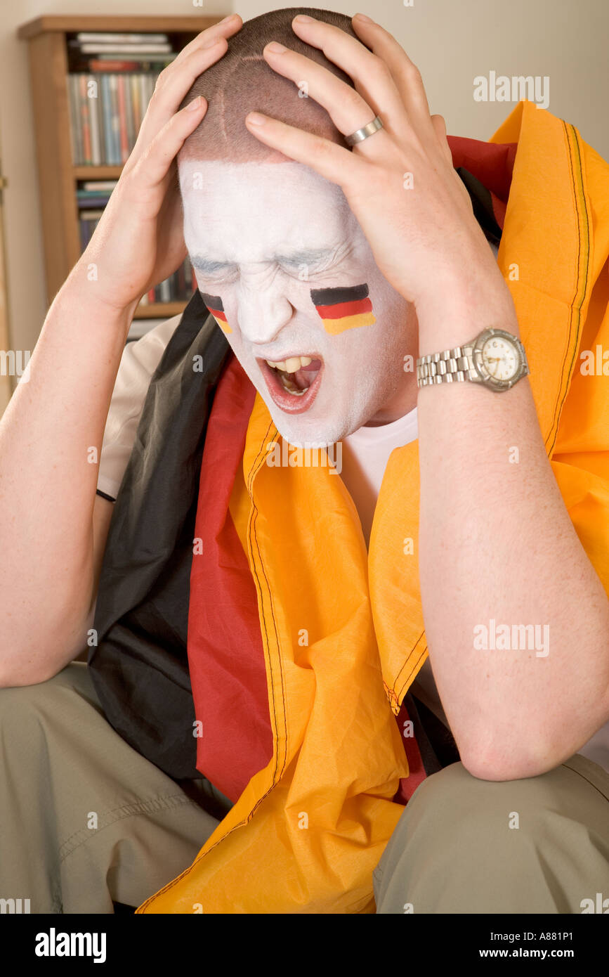 -Modell veröffentlicht. Deutsche Fußball-Fan sitzt auf dem Sofa vor dem Fernseher suchen aufgeregt, als Team gerade verloren hat. Stockfoto