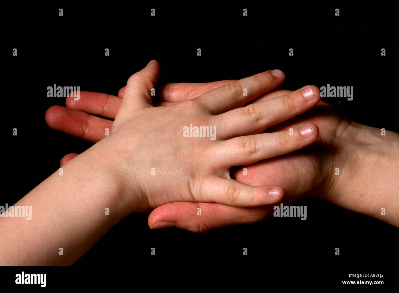 Erwachsenen Hand hält infantilen Hand auf schwarzem Hintergrund Stockfoto