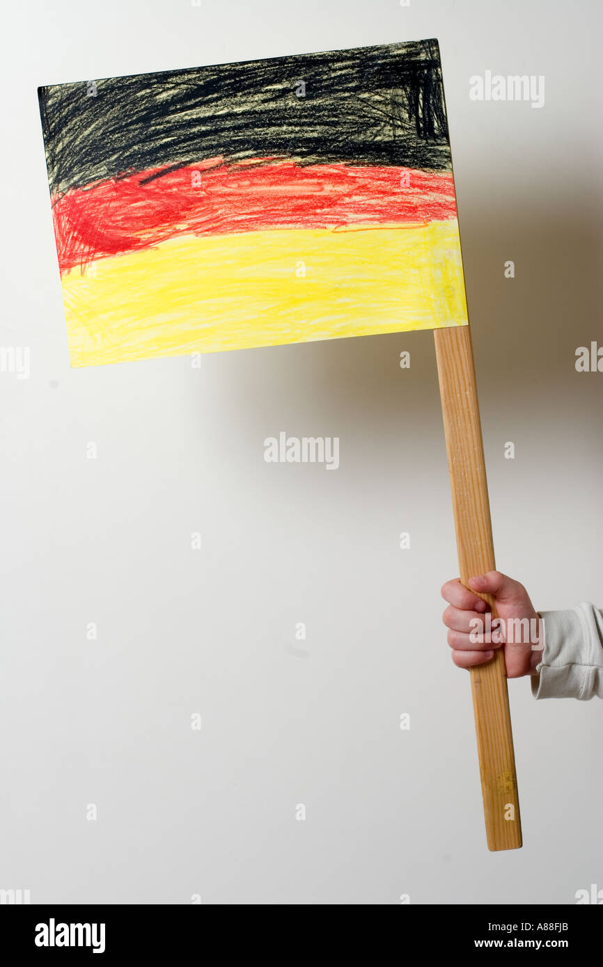 Kinderhand hält eine Selfmade-deutschsprachige Zeitung-Nationalflagge Stockfoto