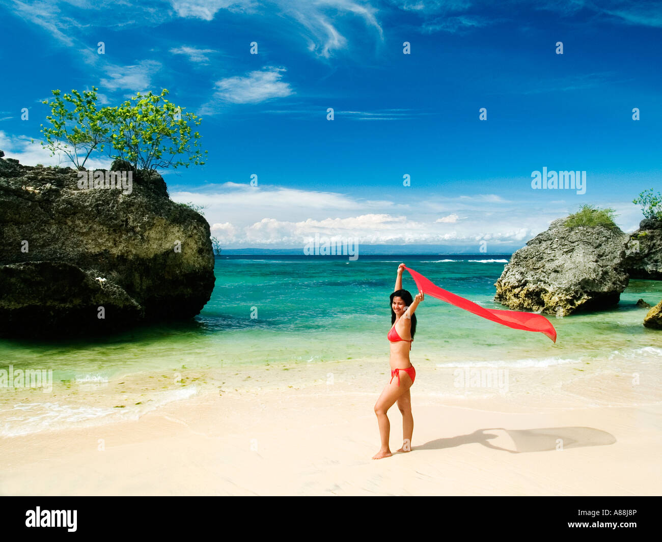 junge Frau im roten Bikini mit roten Sarong bei Padang Padang Strand Bali Indonesien Stockfoto