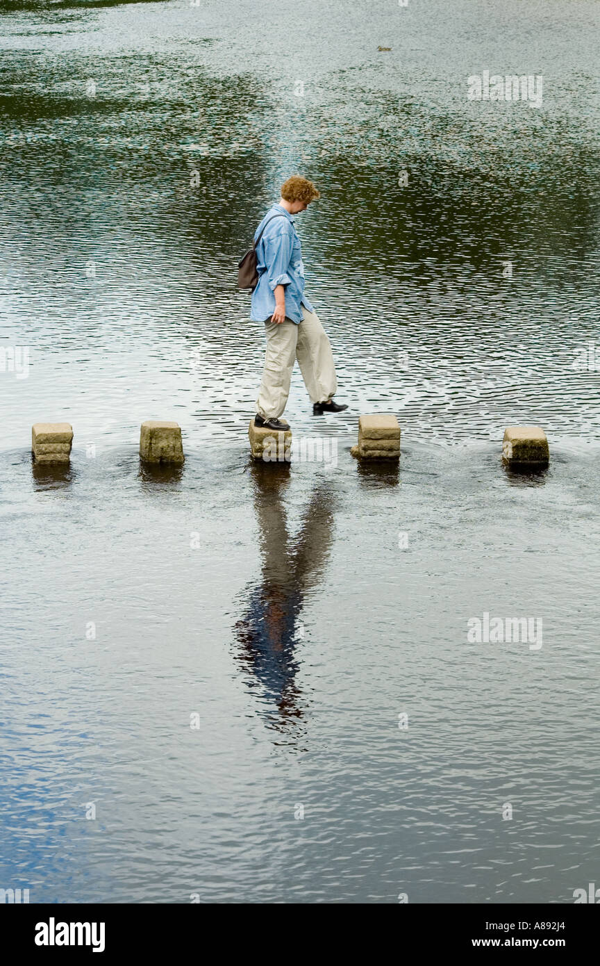Frau balancieren auf Trittsteine auf dem Fluß Wharfe bei Bolton Abbey, Wharfedale, Yorkshire Dales National Park, England, UK Stockfoto