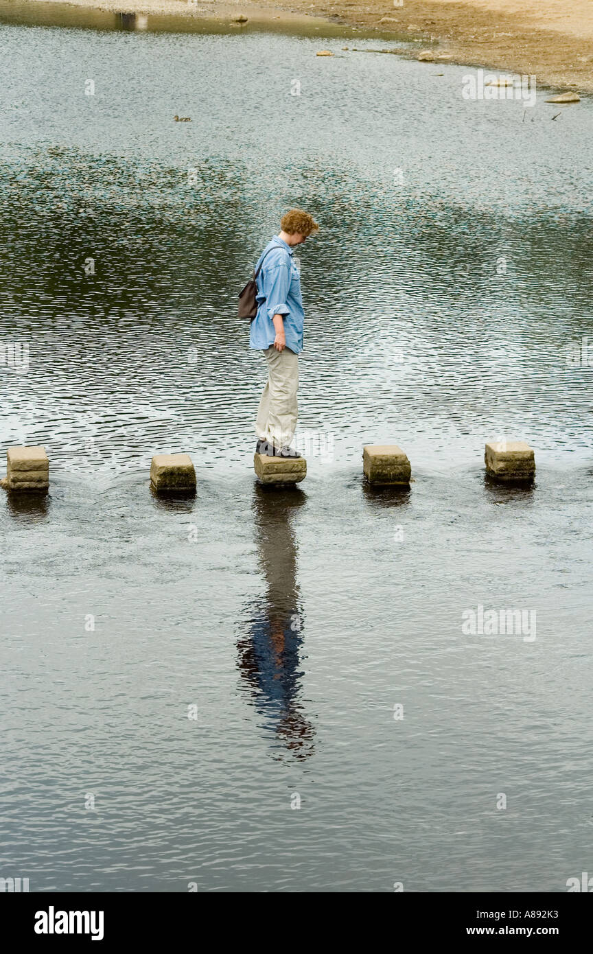 Frau balancieren auf Trittsteine auf dem Fluß Wharfe bei Bolton Abbey, Wharfedale, Yorkshire Dales National Park, England, UK Stockfoto