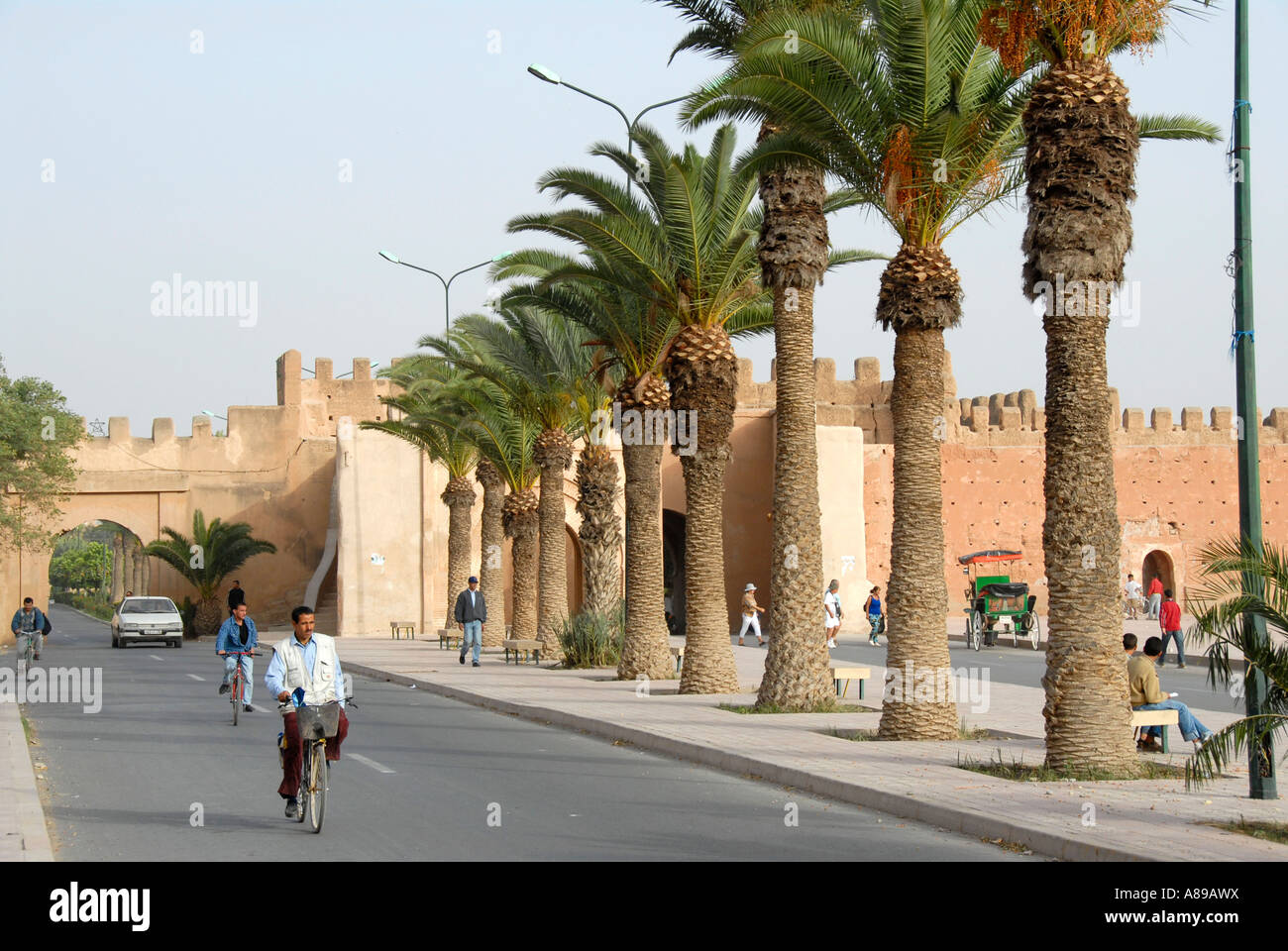 Radfahrer auf der Straße unter Palmen und alten Burgwall Taroudant Marokko Stockfoto